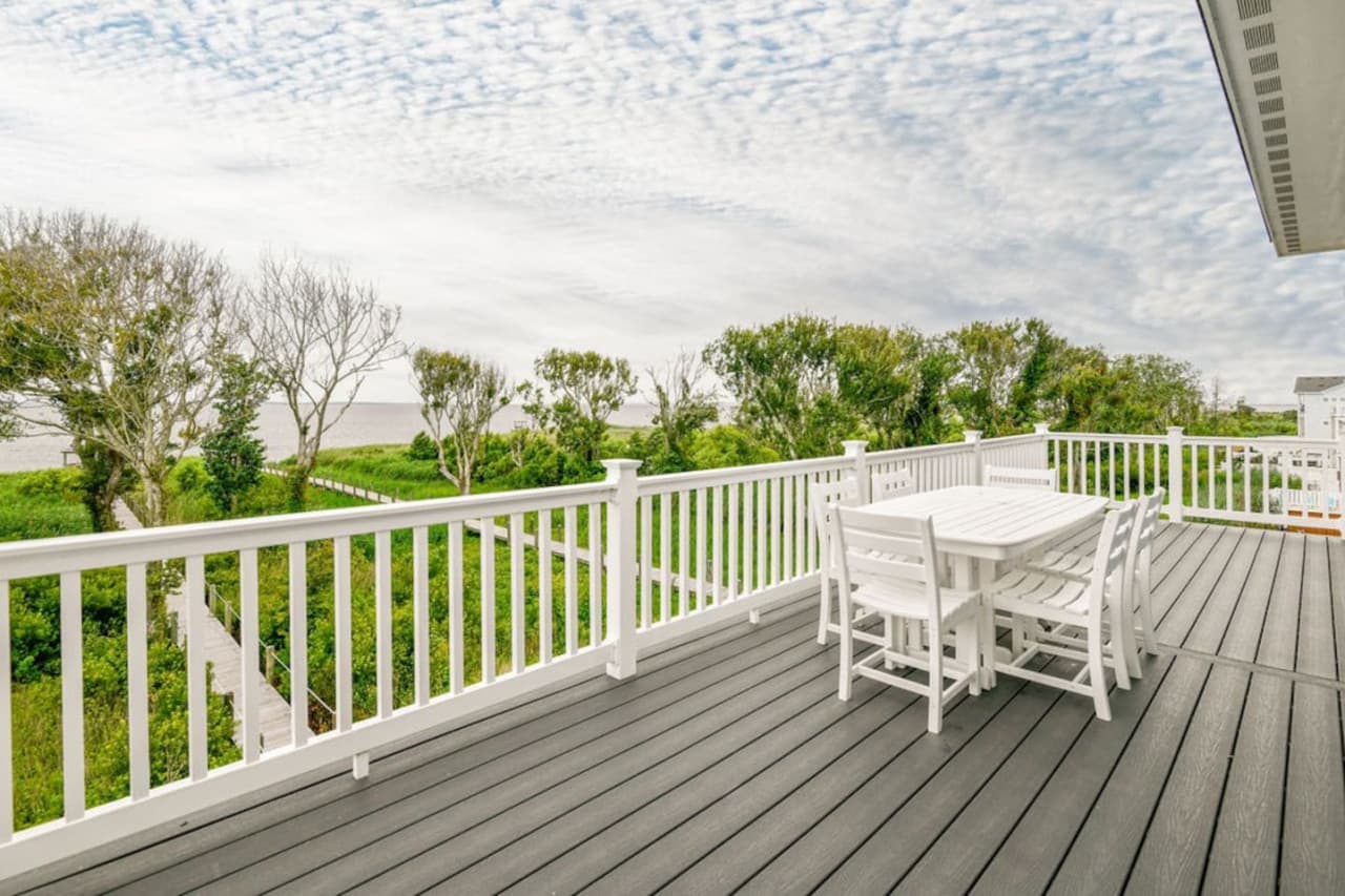 Upper deck w/ outdoor dining, surrounded by greenery and coastal air.