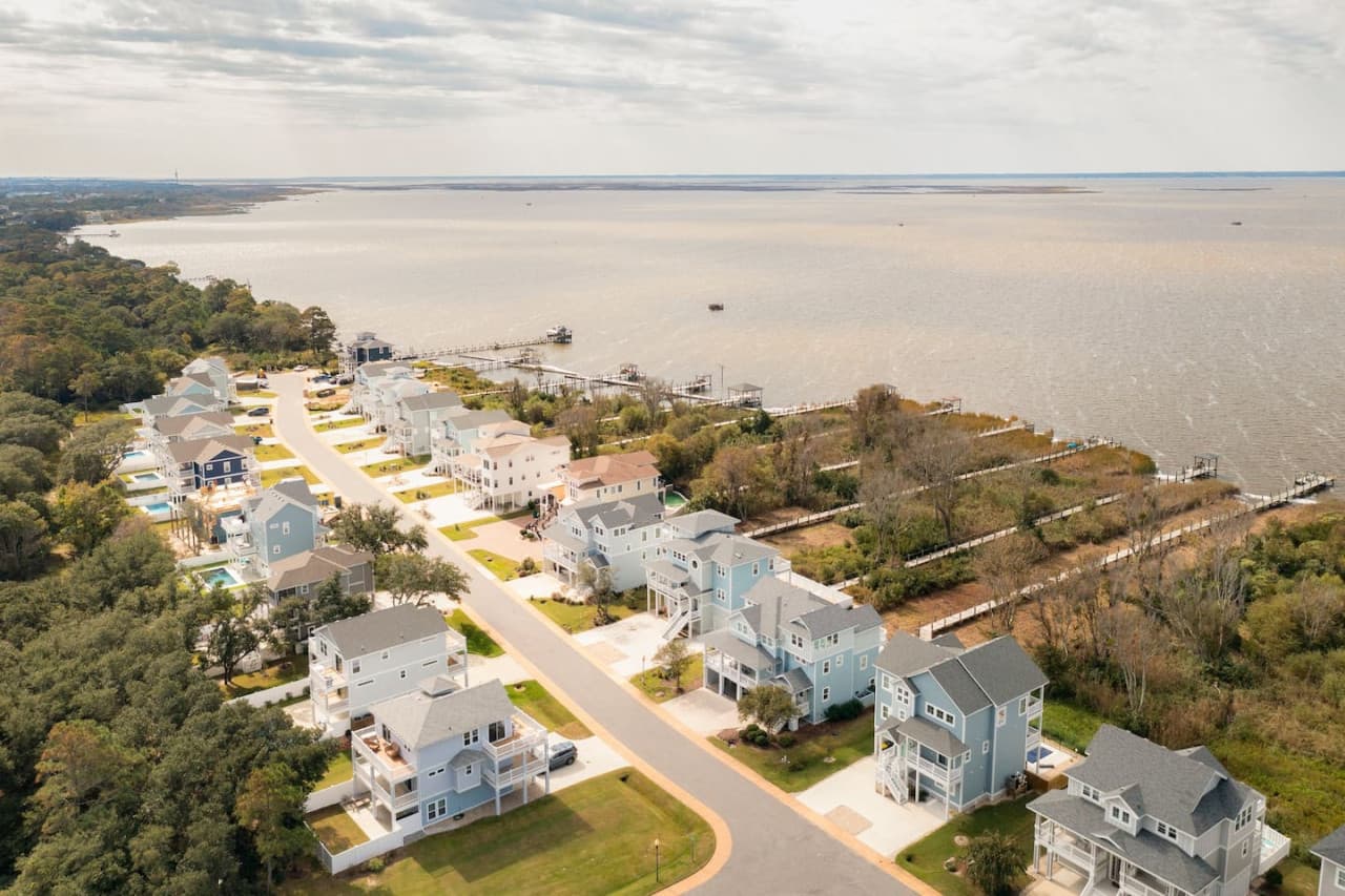 Elevated aerial view showcasing the surrounding homes, water nearby & the relaxed coastal setting.