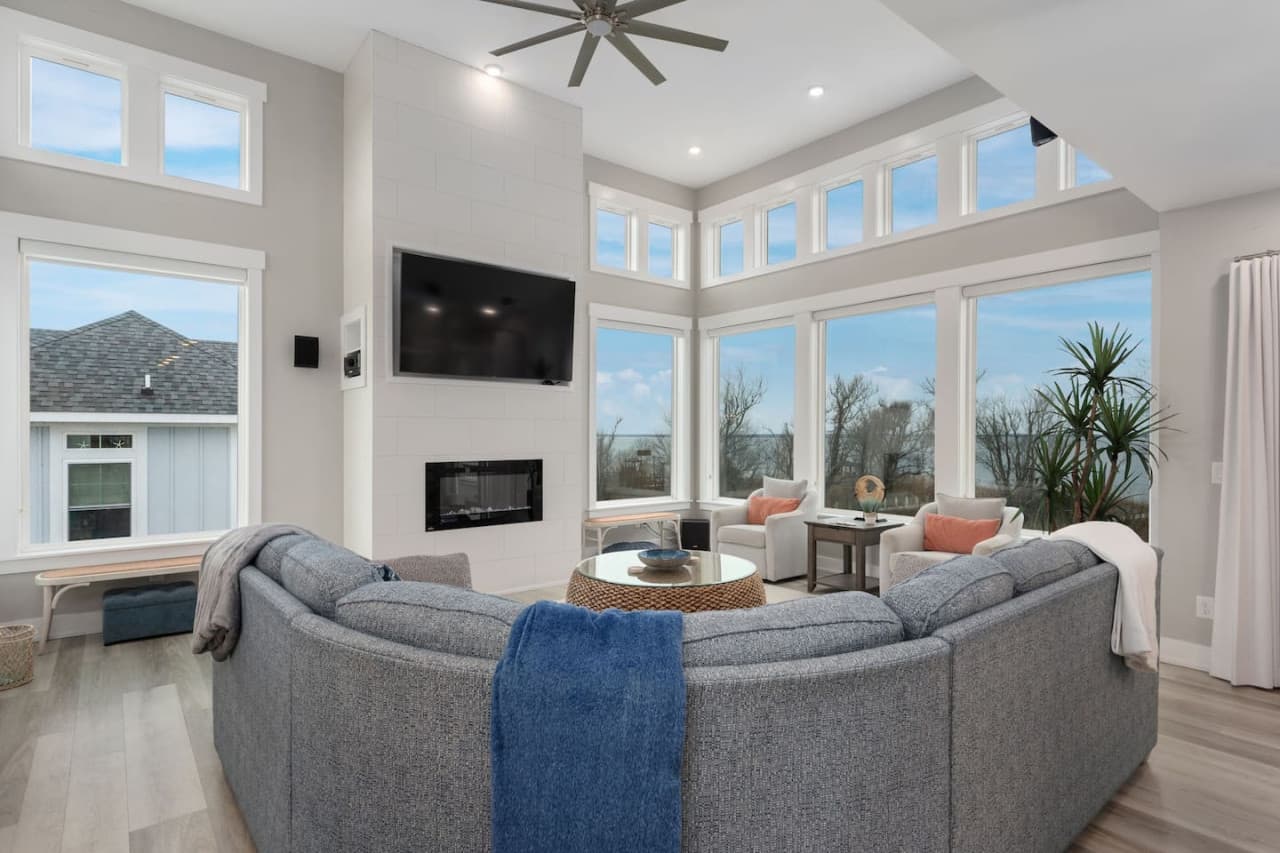 Spacious living room w/ sectional seating, wall-mounted TV & abundant natural light.