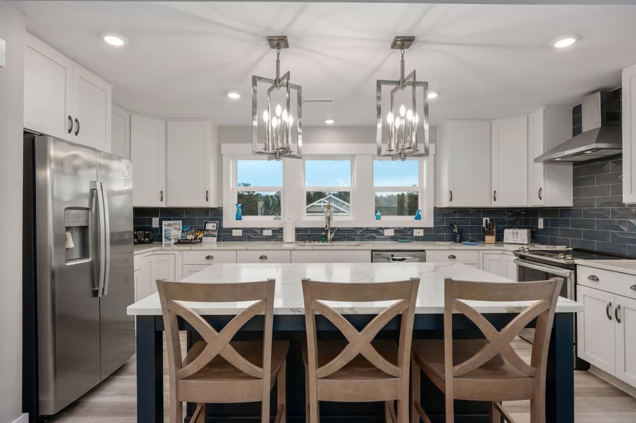 Modern kitchen view w/ stainless appliances, generous island & bright, open design.