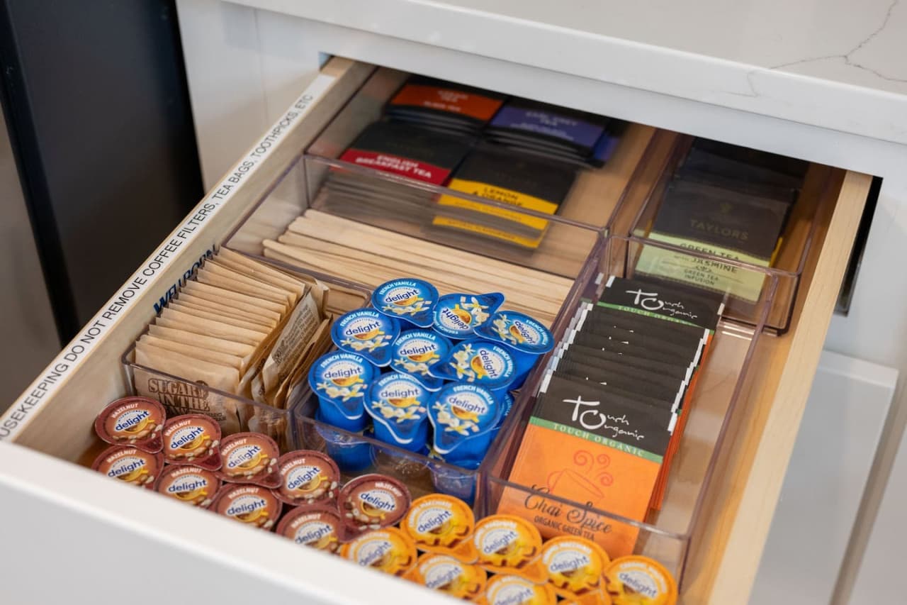 Neatly stocked beverage drawer w/ coffee pods, tea options, sweeteners, & creamers for an easy morning start.