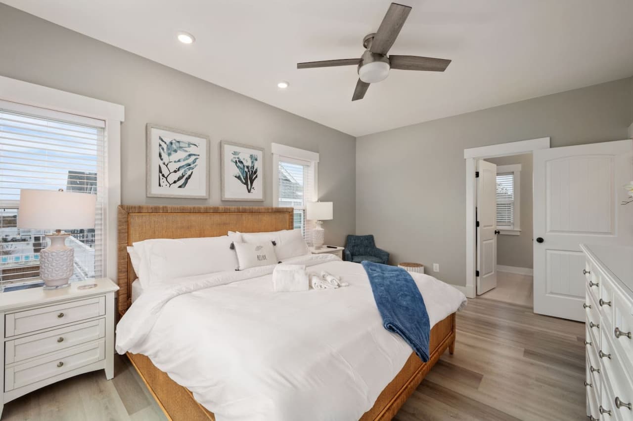 Bright, airy bedroom w/ cozy bedding, coastal art & plenty of natural light.