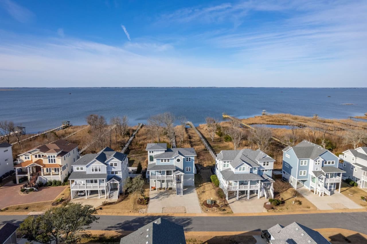 Elevated aerial view showcasing the homes below & water stretching beyond.