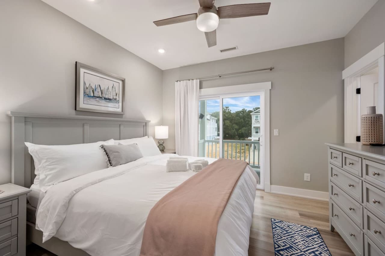 Restful bedroom w/ plush white bedding, roomy dresser & a slider out to the deck.