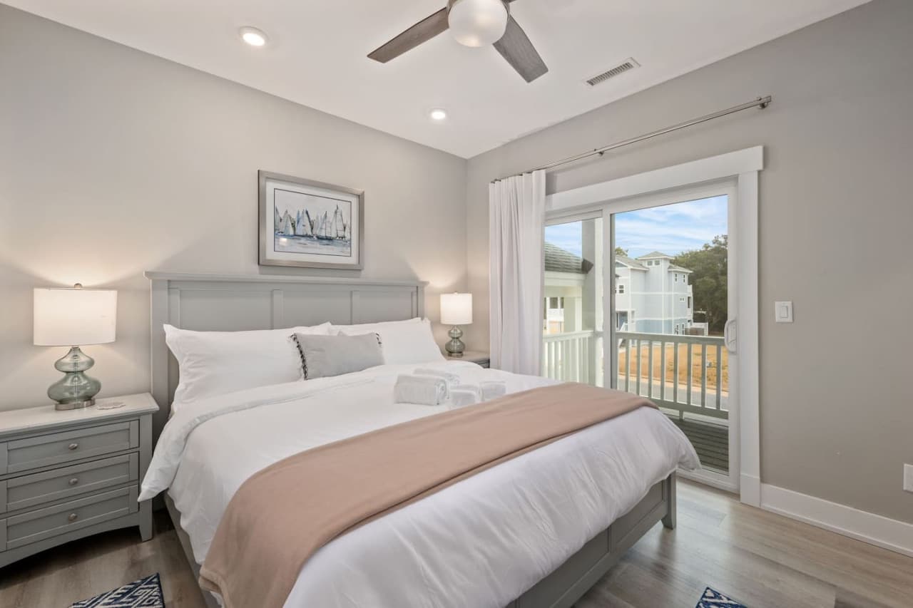 Bright bedroom w/ matching nightstand lamps, crisp linens & deck access just steps away.