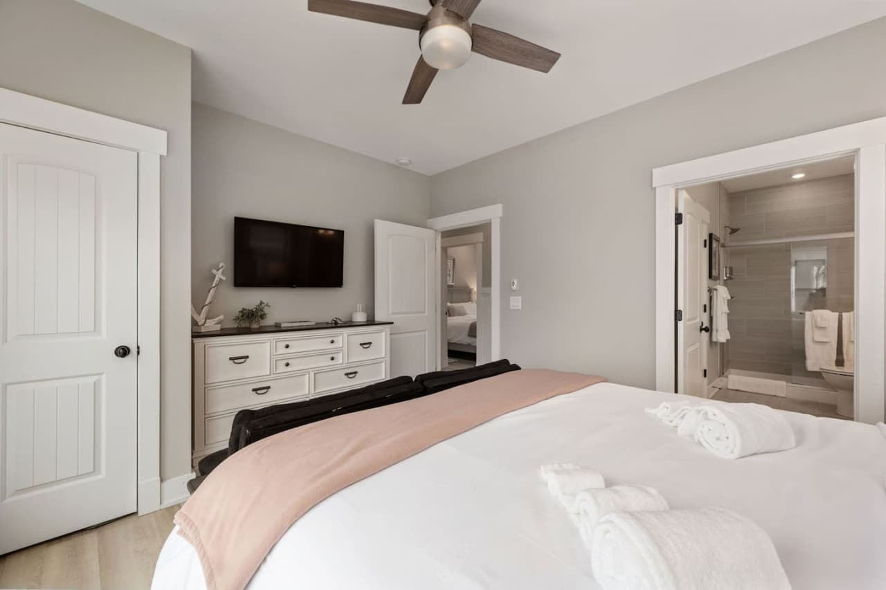 Bedroom w/ wall-mounted TV, long dresser & a private ensuite bath just through the door.