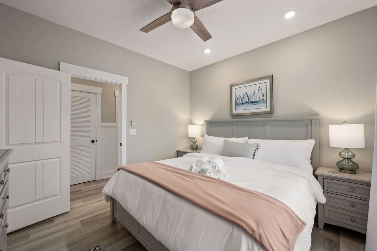 Calm bedroom w/ ceiling fan, soft blush throw & double closet doors for easy unpacking.