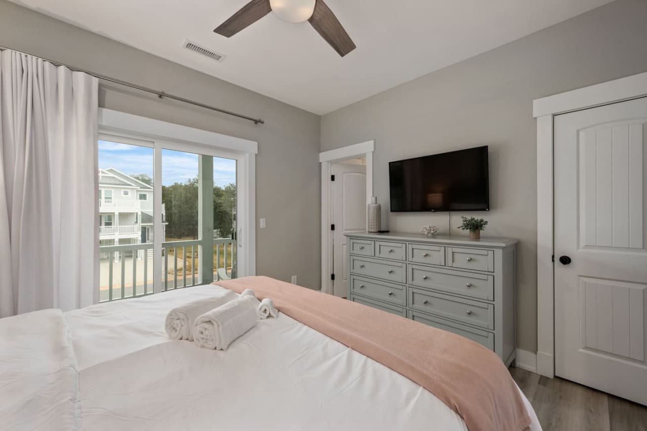 Comfortable bedroom w/ TV atop the dresser, framed art & soft light through the window.
