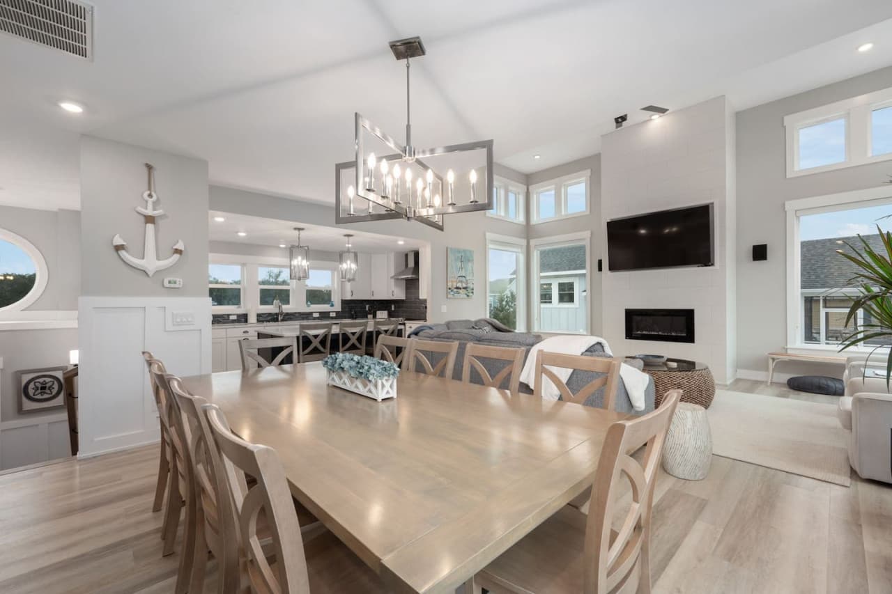 Open dining & living space w/ vaulted ceiling, chandelier over the long table & fireplace.