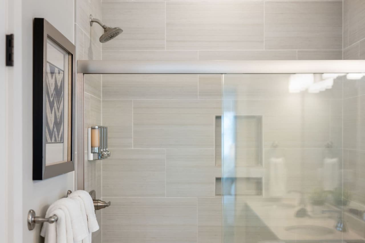 Tiled walk-in shower w/ glass surround & fresh towels within arm's reach.