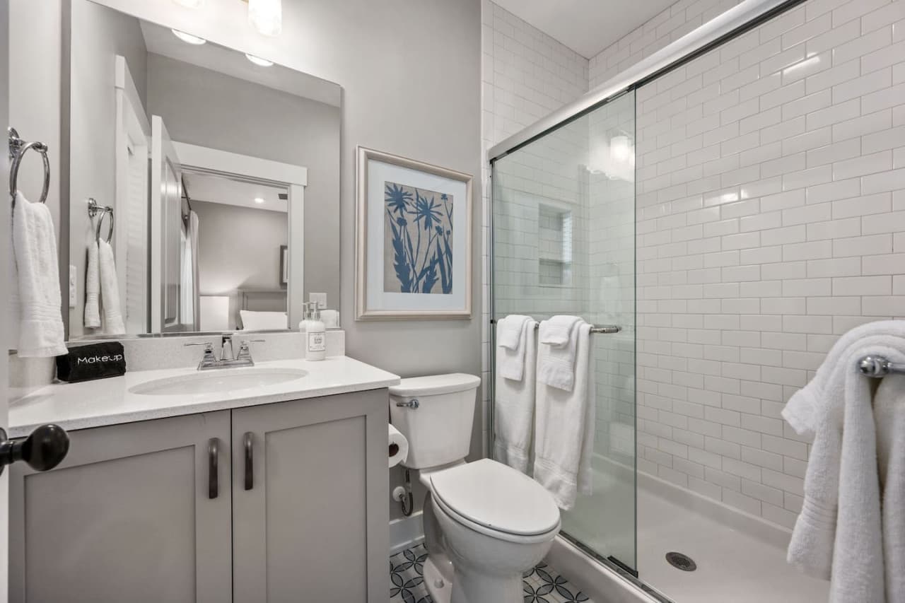 Full bath w/ vanity, glass-door walk-in shower & stacked towels ready to go.