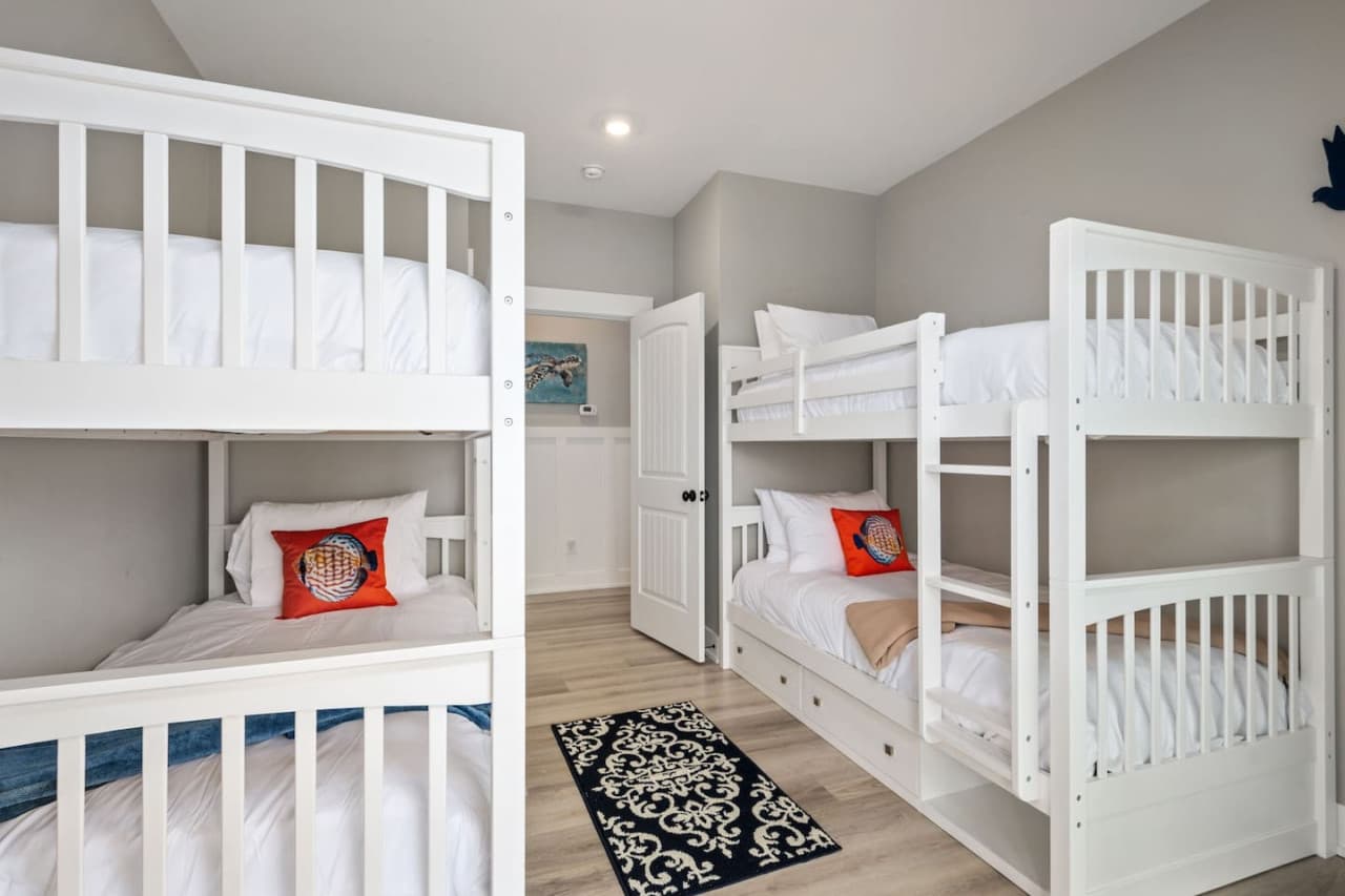 Bunk room w/ two sets of bunk beds, pull-out trundle & a patterned rug underfoot.