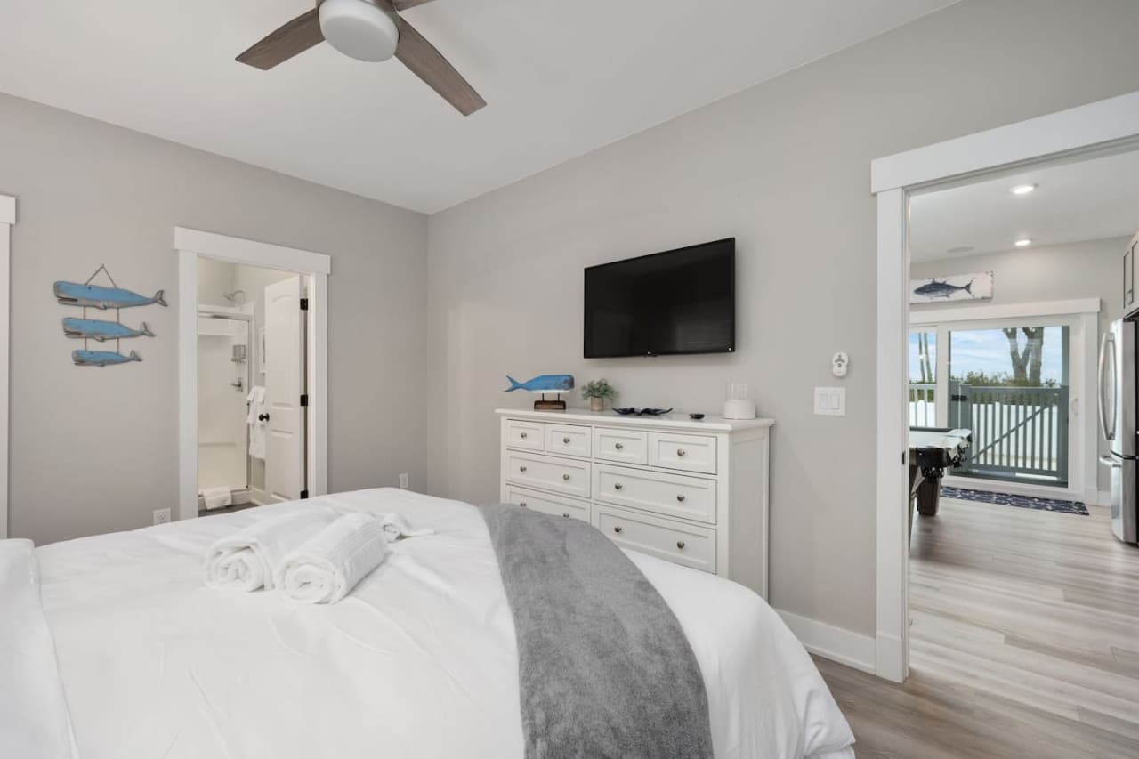 Bedroom w/ TV above the dresser, ensuite bath & a slider opening onto the deck.