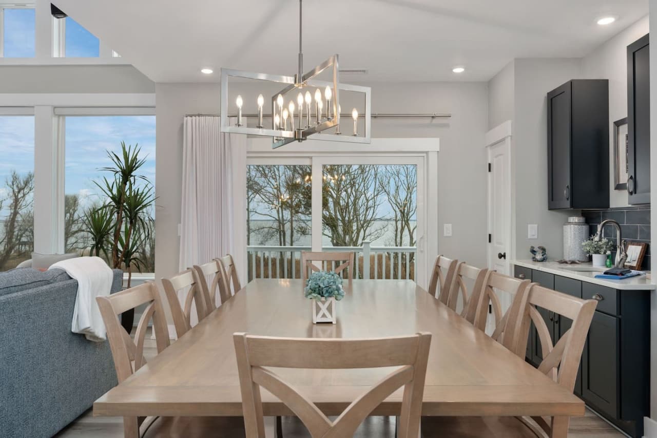 Long dining table for ten w/ chandelier above & a wet bar w/ coffee station alongside.