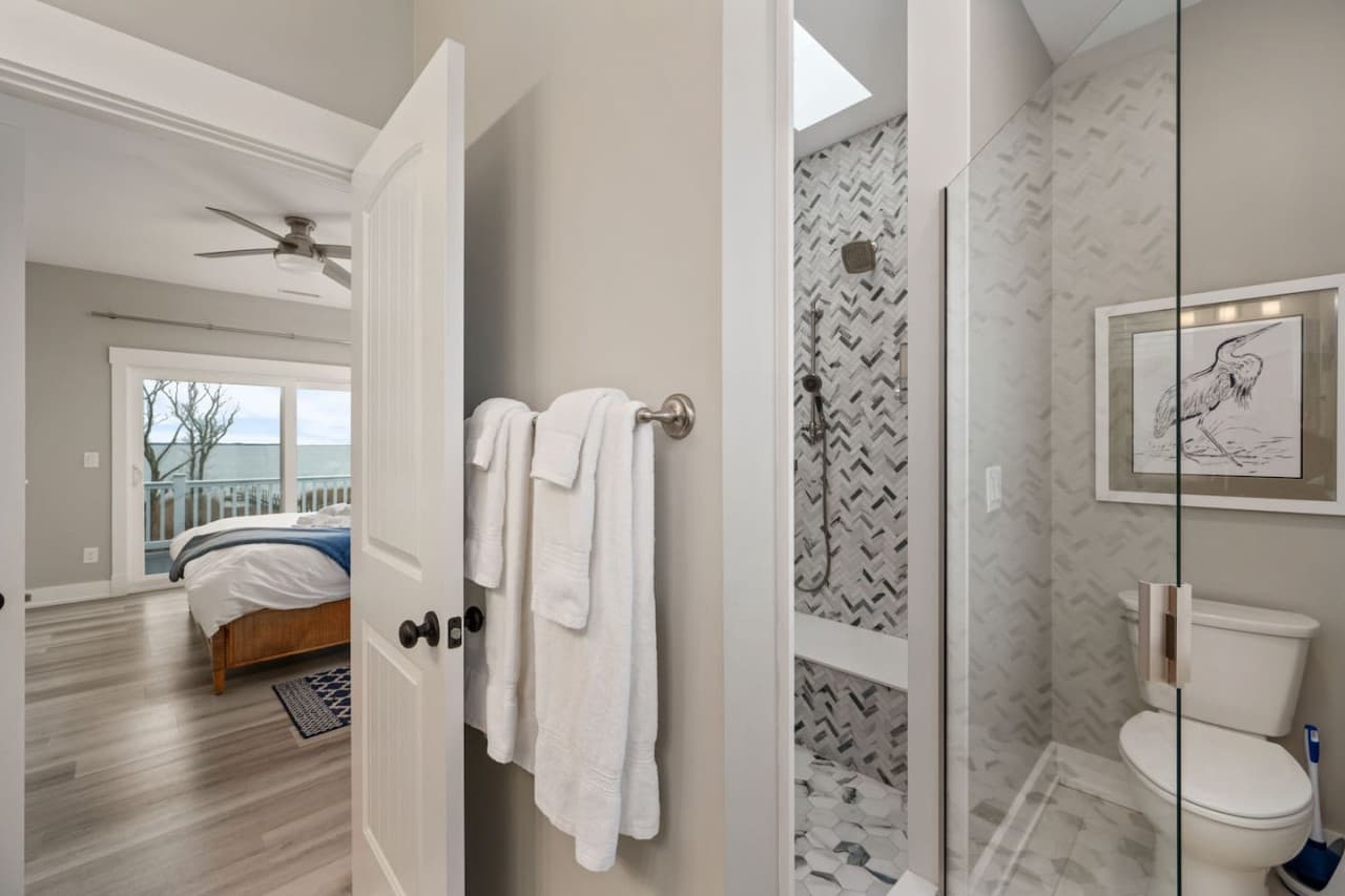 Ensuite bath just off the bedroom w/ mosaic-tiled shower & towels on the bar.