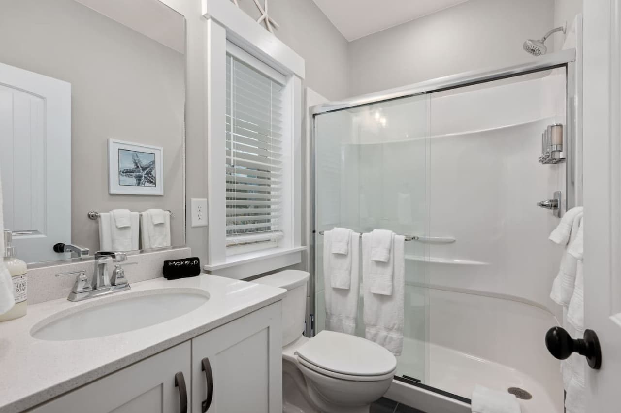 Full bath w/ vanity, glass-door shower & starfish art for a light coastal touch.
