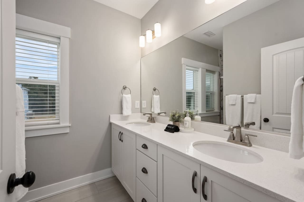 Bath w/ long vanity, wide mirror & sconce lighting, towels stacked & ready.