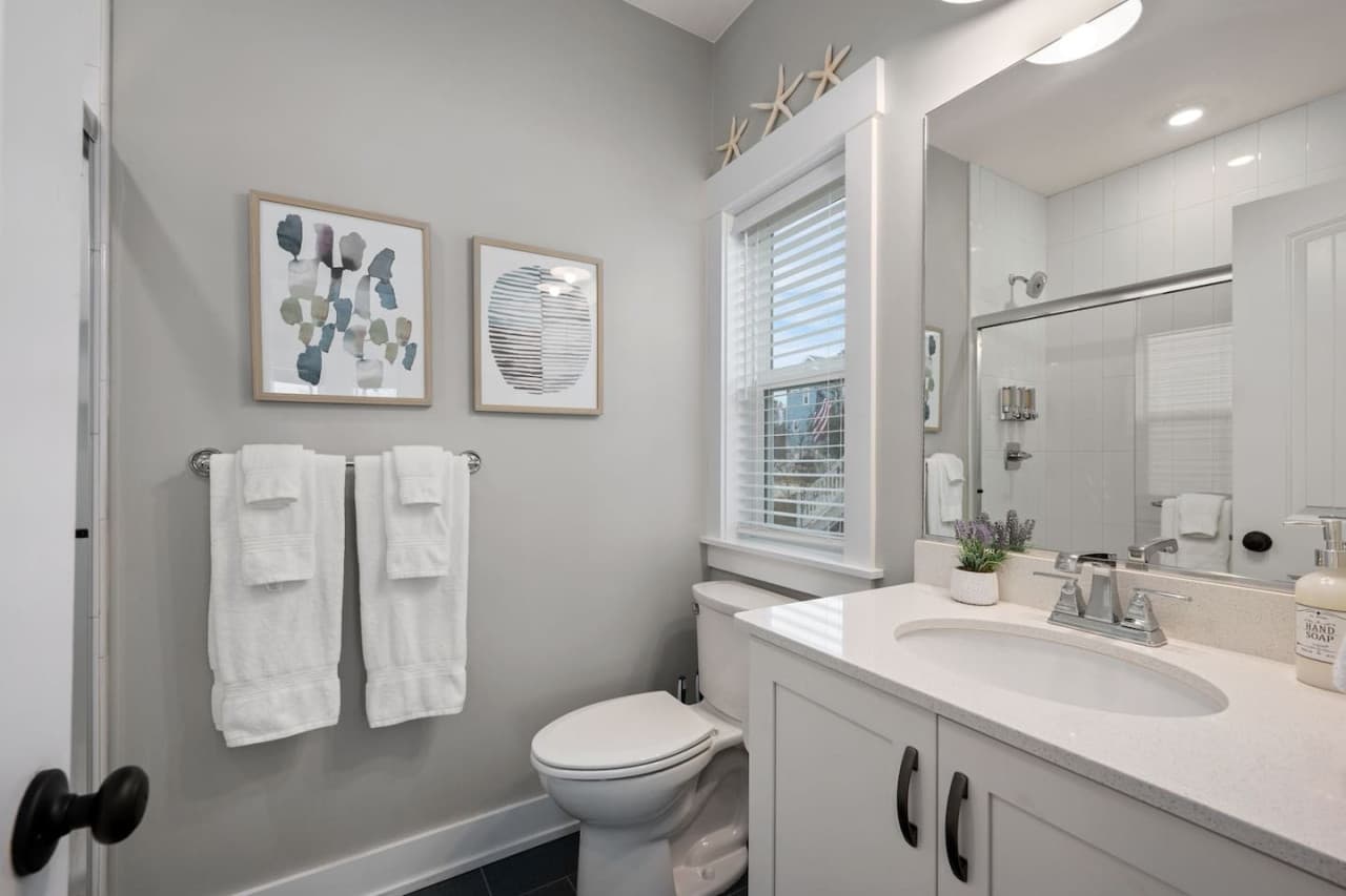 Bath w/ glass-door shower, framed art & a towel bar within reach of the vanity.