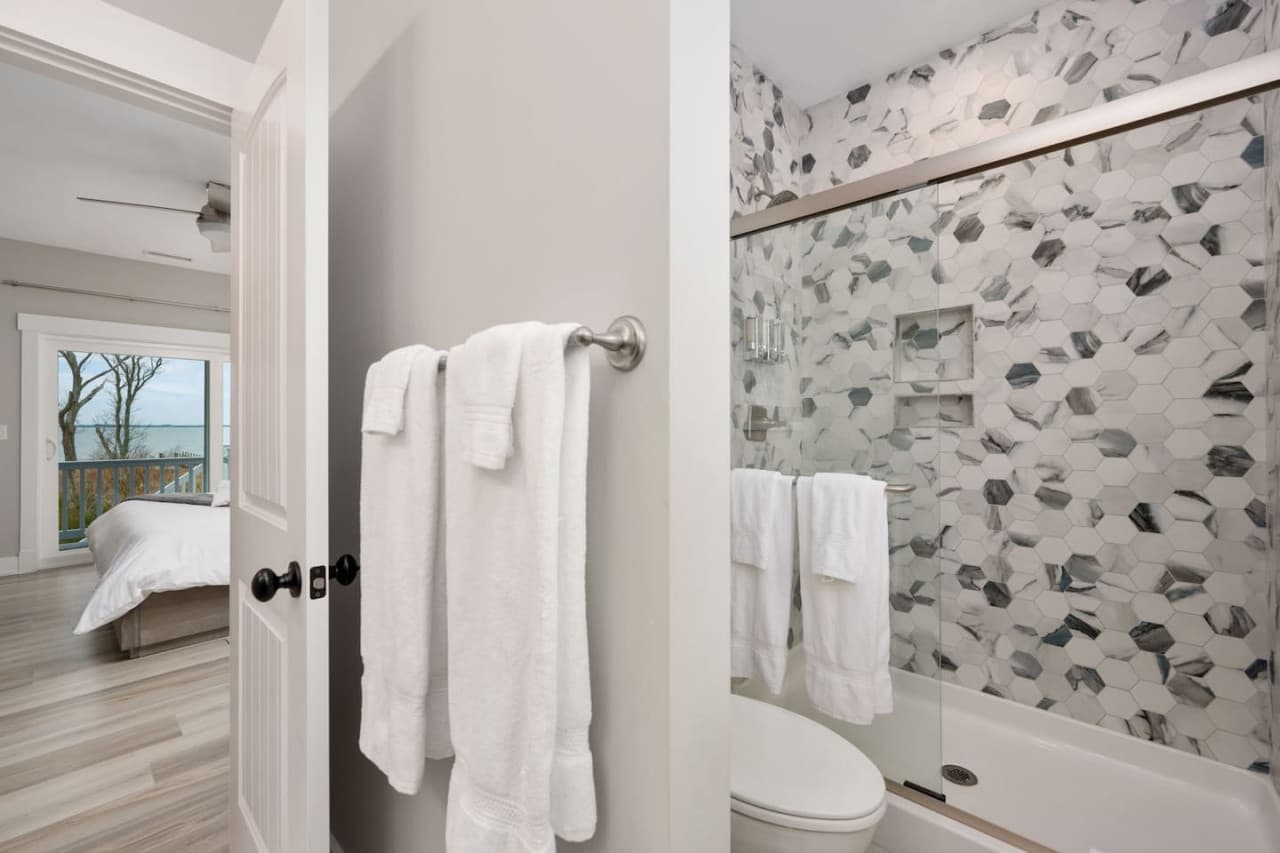 Bath w/ pebble-tile shower surround & towel bar, opening straight into the bedroom.