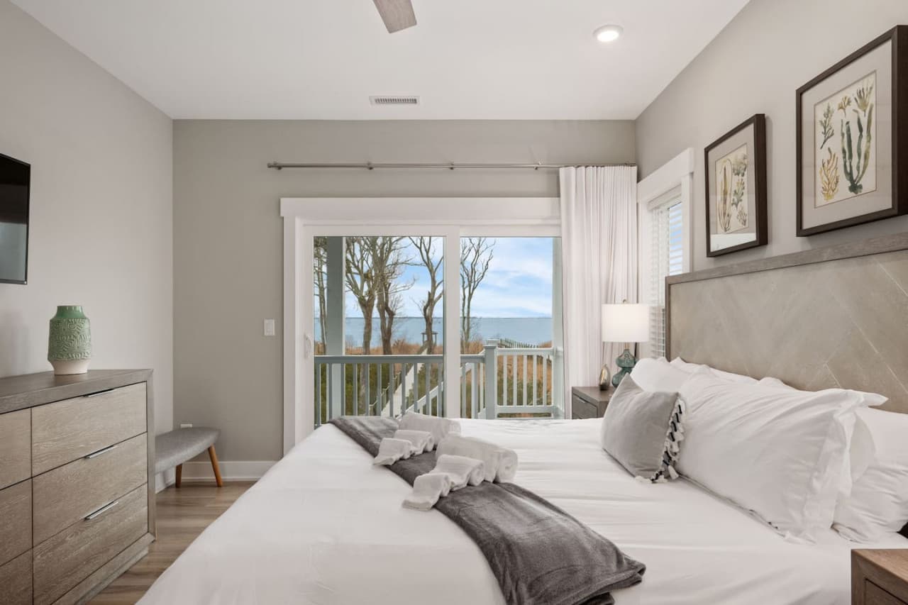 Bedroom w/ upholstered headboard, botanical prints & a slider out to the deck.