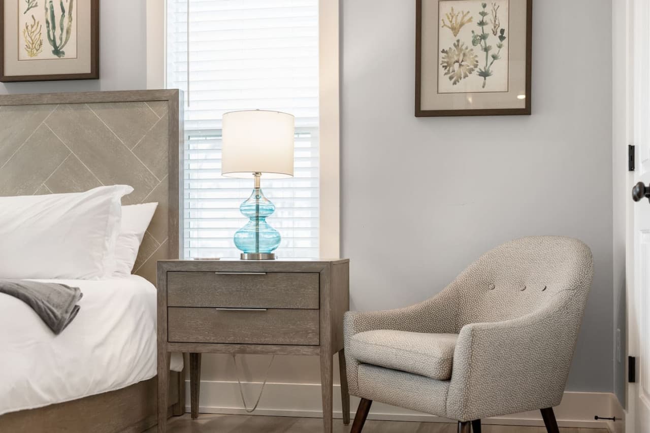 Cozy corner detail w/ boucle accent chair, glass lamp & nightstand by the window.