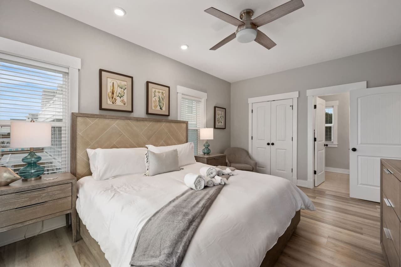 Bedroom w/ chevron upholstered headboard, botanical art & closet plus ensuite doors.