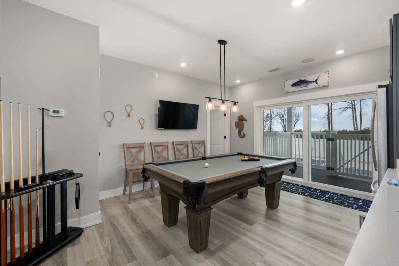 Game room w/ pool table, cue rack, mounted TV & a slider out to the deck.