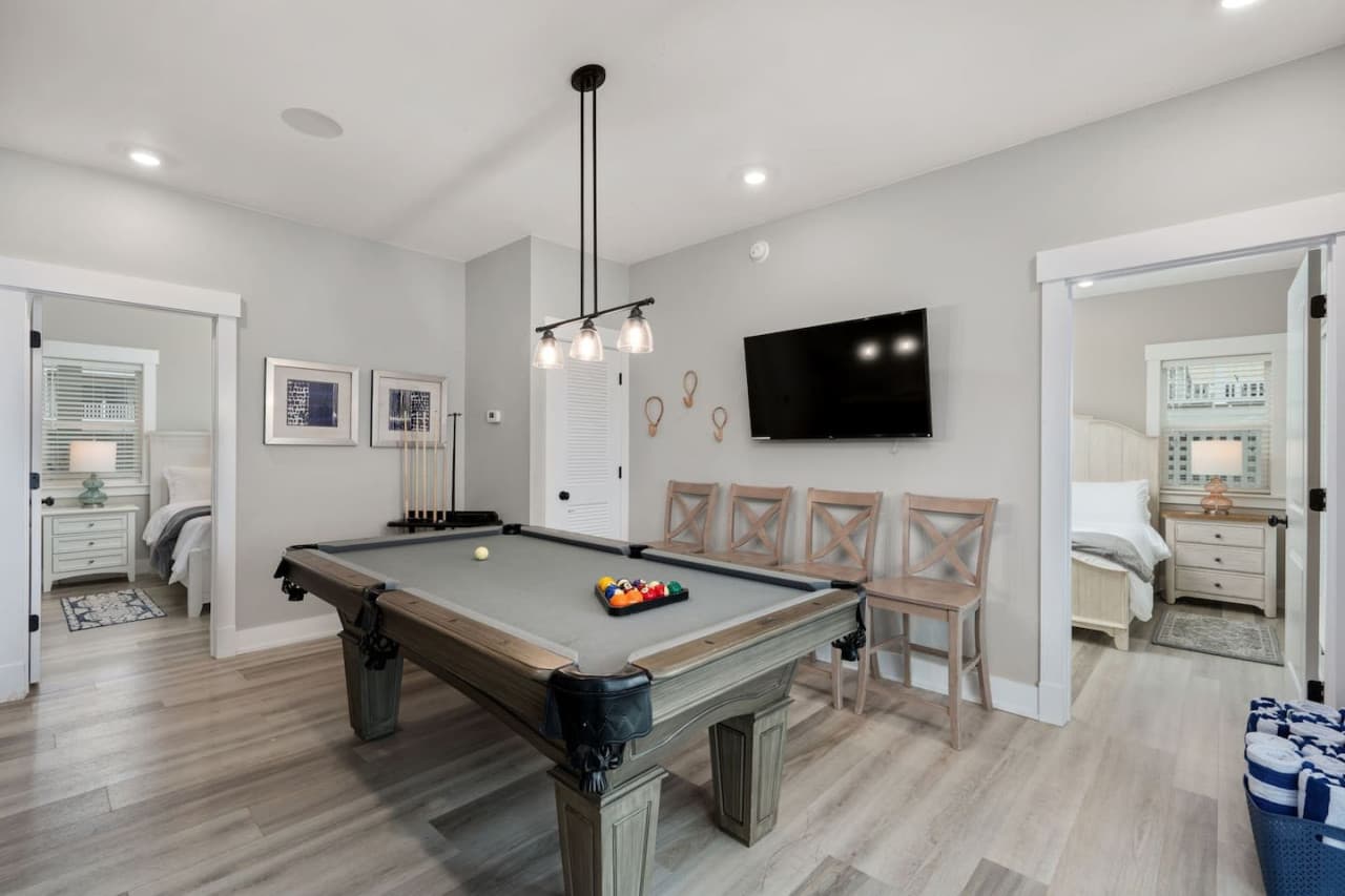 Pool table under pendant lighting w/ bar seating & a bedroom just off the game room.