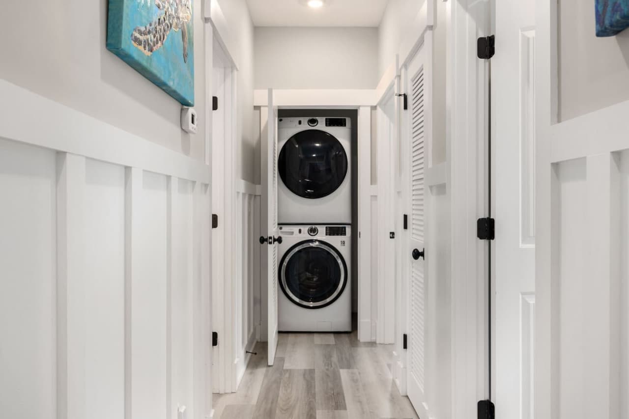 Hallway laundry w/ stacked washer & dryer tucked behind bifold doors.