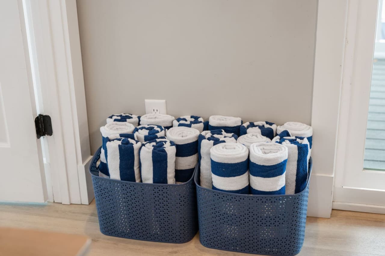 Baskets of rolled navy-striped towels by the door, ready for the pool or the dock.