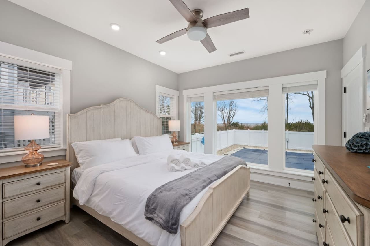 Bedroom w/ arched headboard & French doors opening right onto the pool deck.