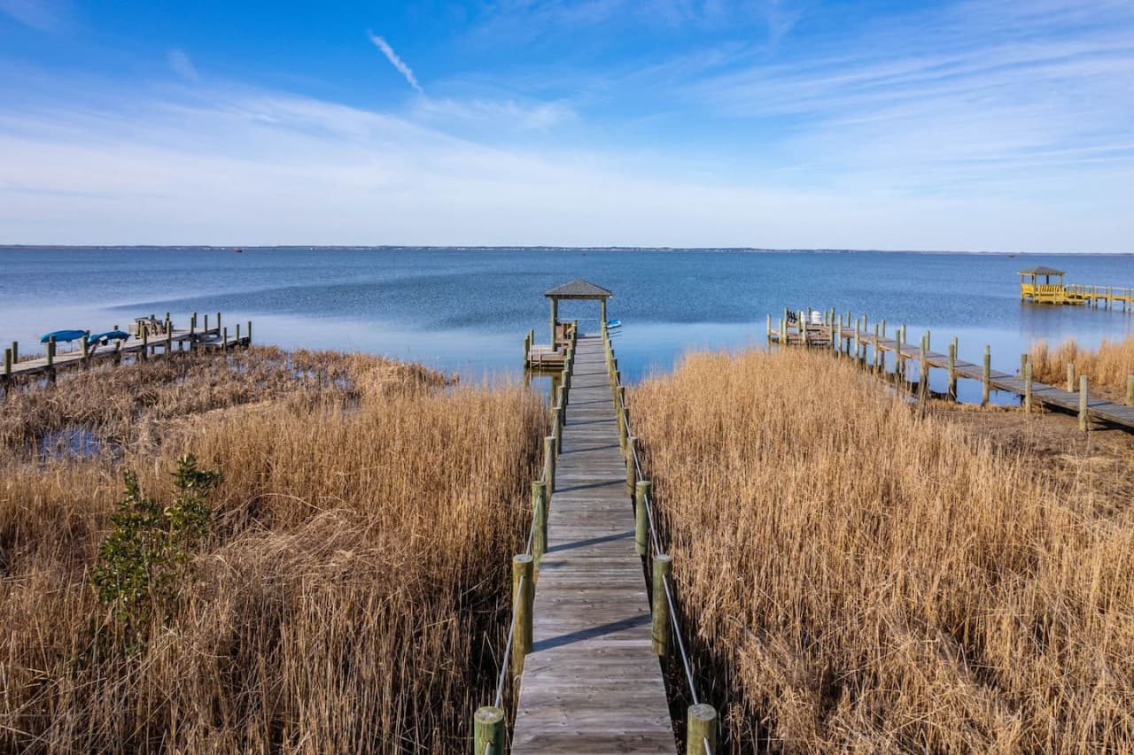 Private dock running out through the marsh grass over the calm water of the sound.