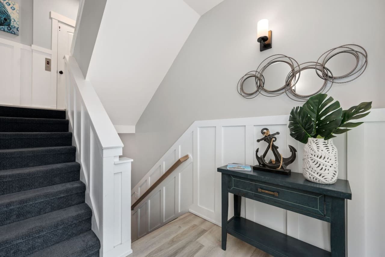 Stair landing w/ navy console table, nautical accents & carpeted steps up.