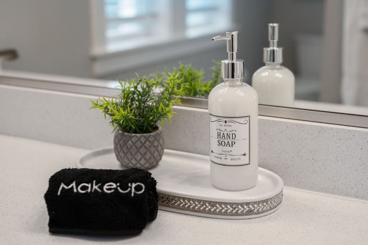 Close-up of the vanity tray w/ hand soap, greenery & a makeup cloth provided.