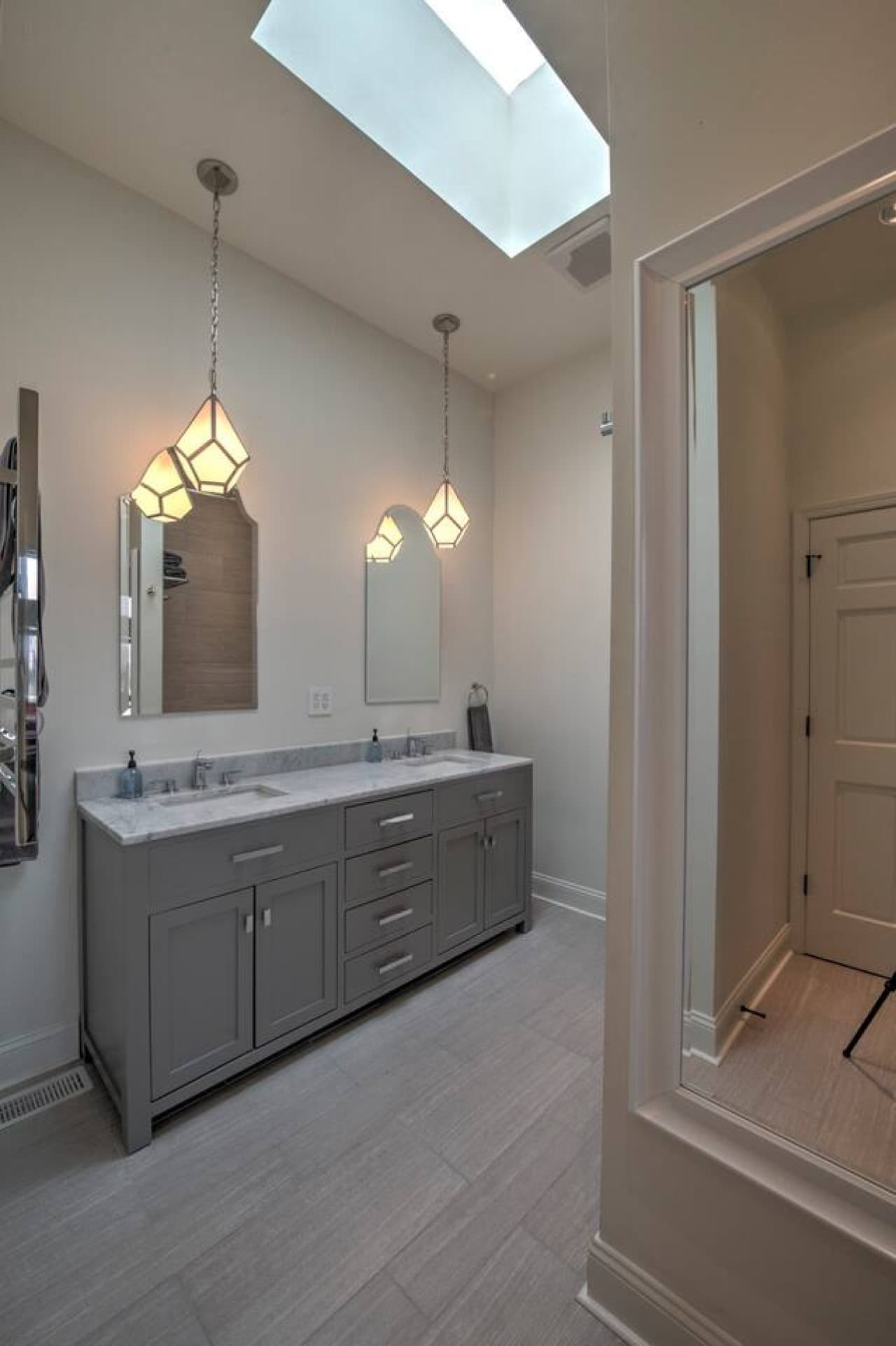 The 2nd floor bathroom features a jetted tub, heated tile floors and towel bars, a dual vanity, and skylight.