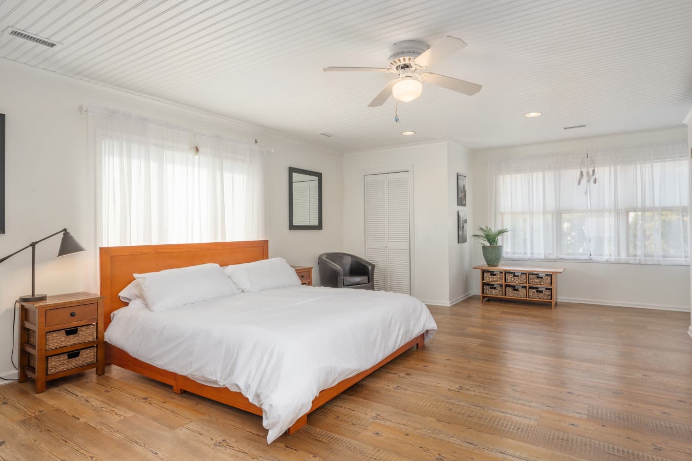 Spacious bedroom w/ a cozy bed, ceiling fan, & plenty of natural light for easy mornings.