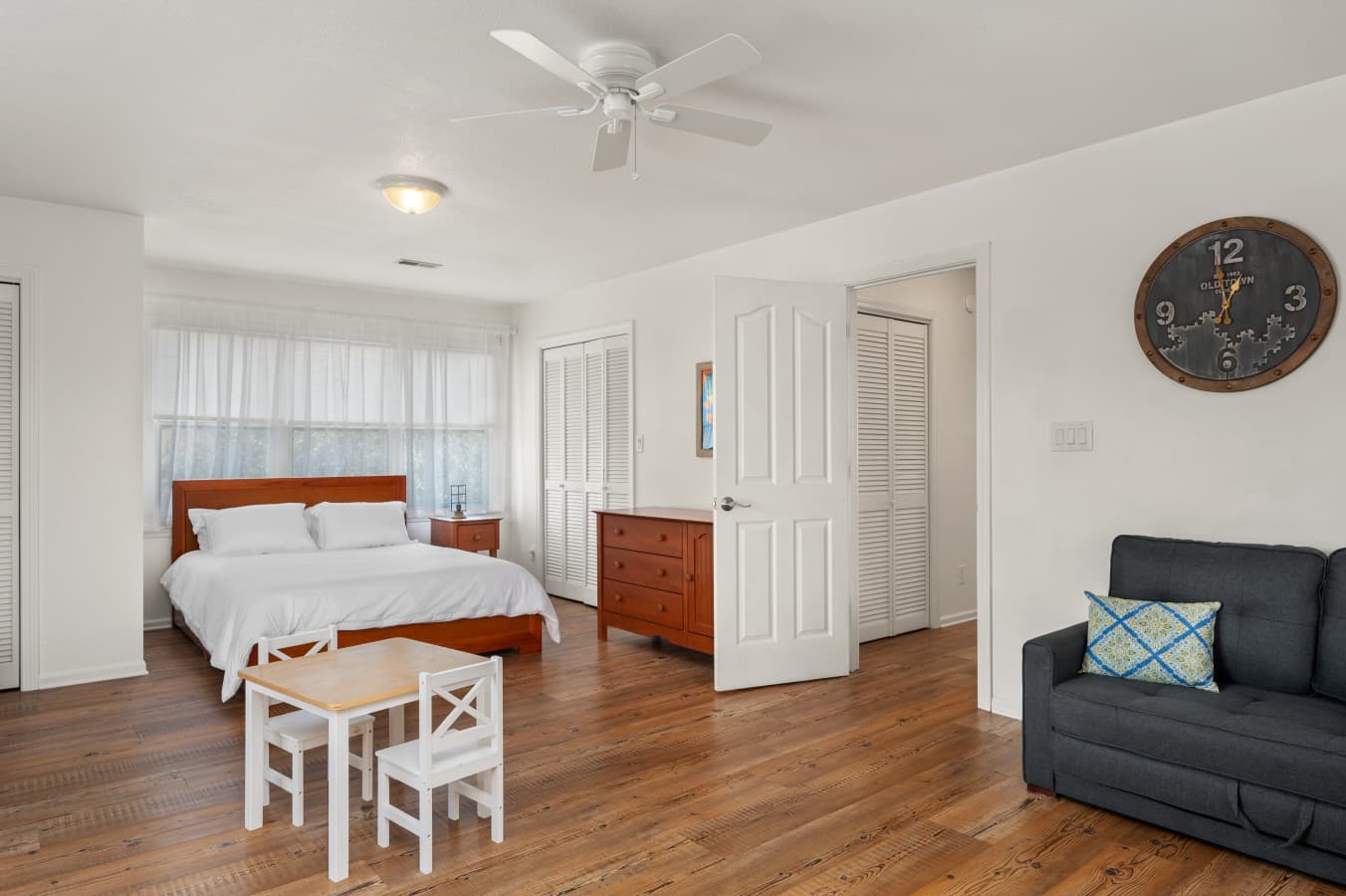 Airy bedroom w/ wood floors, soft linens, & simple decor for a calm, restful feel.