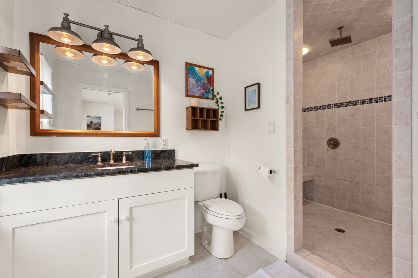 Spacious bathroom w/ a tiled walk-in shower, bright vanity lighting, & a clean, airy layout.