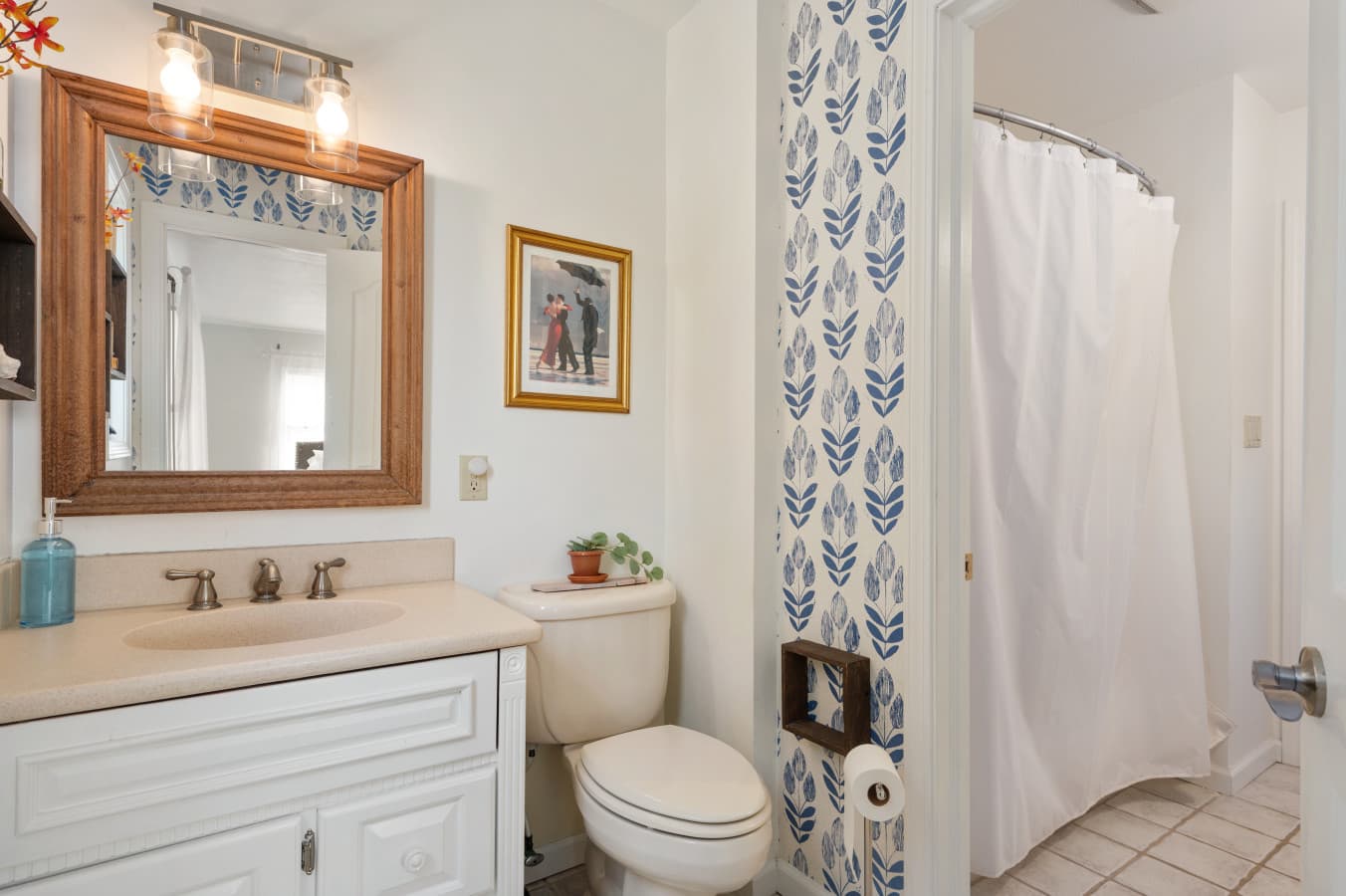 Fresh bathroom w/ vanity, mirror, & shower combo, finished w/ light coastal touches.