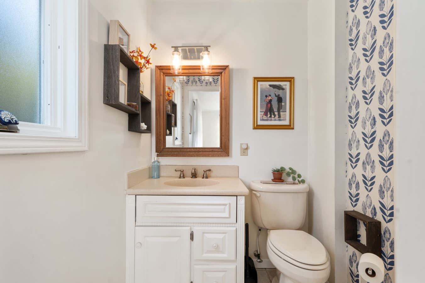 Clean bathroom vanity w/ mirror, warm lighting, & simple coastal accents.