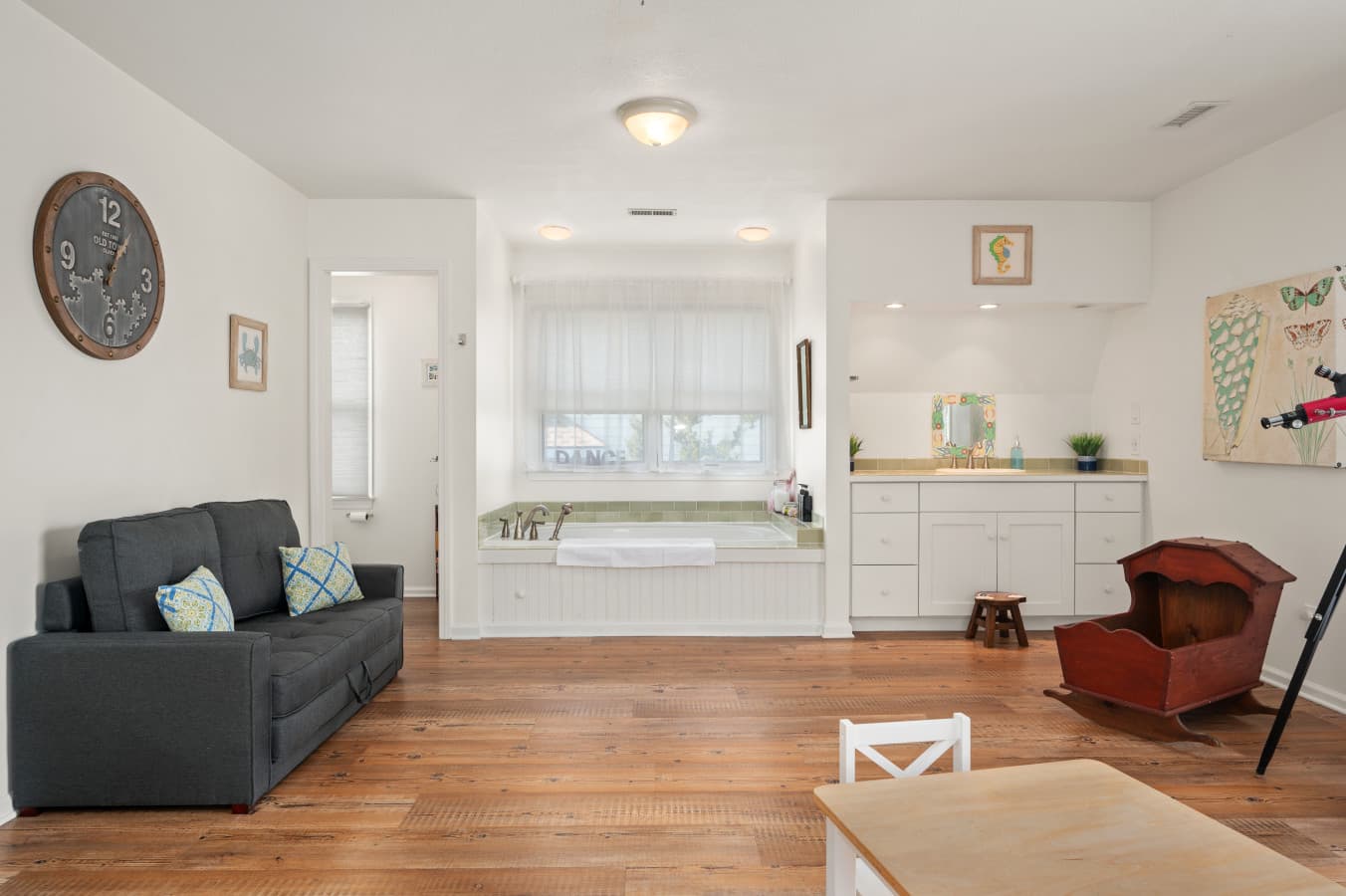 Welcoming living area w/ seating and a clear view into the bright bedroom beyond.