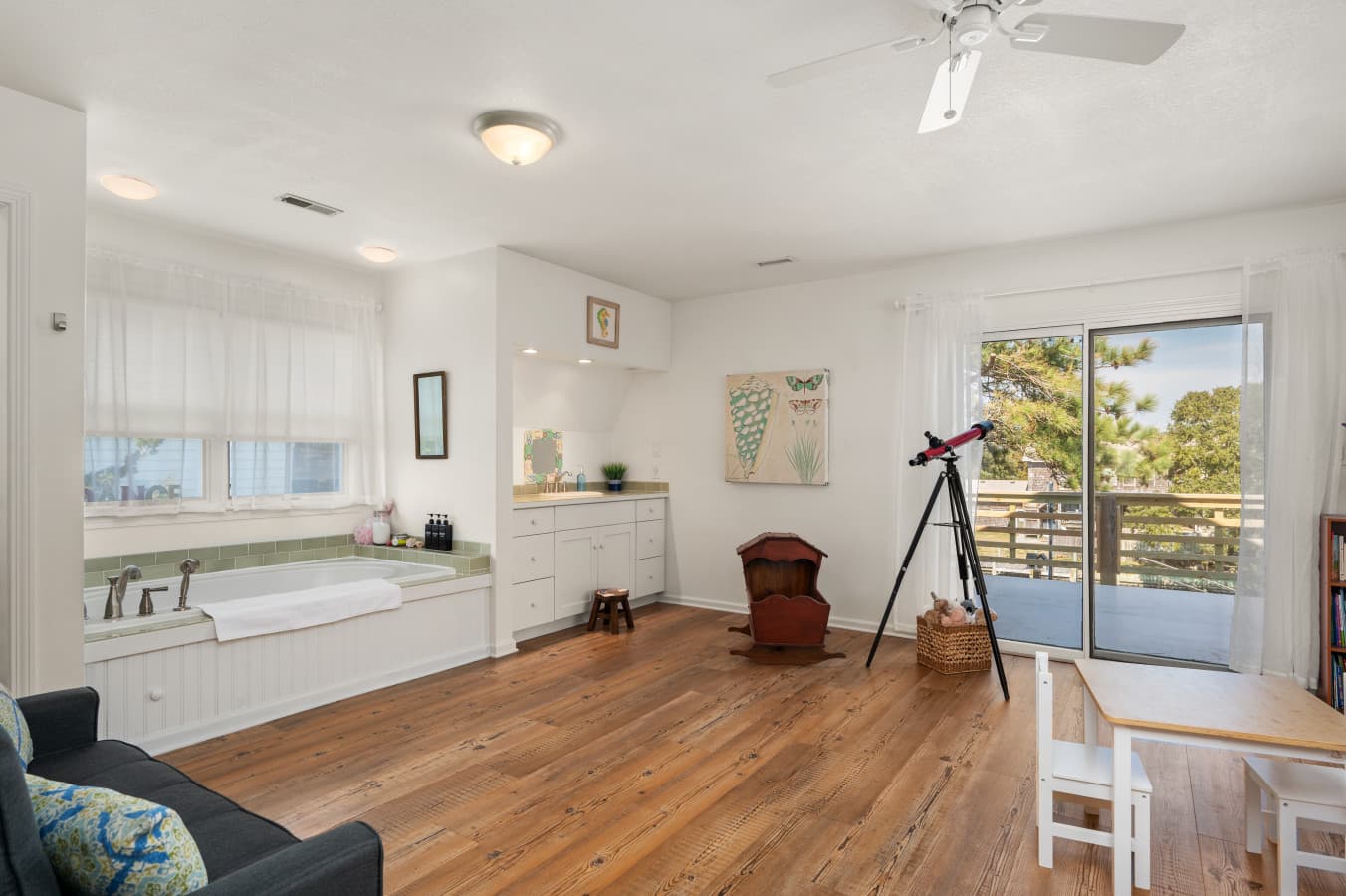 Spacious living room w/ comfy seating and large windows opening to outdoor greenery.