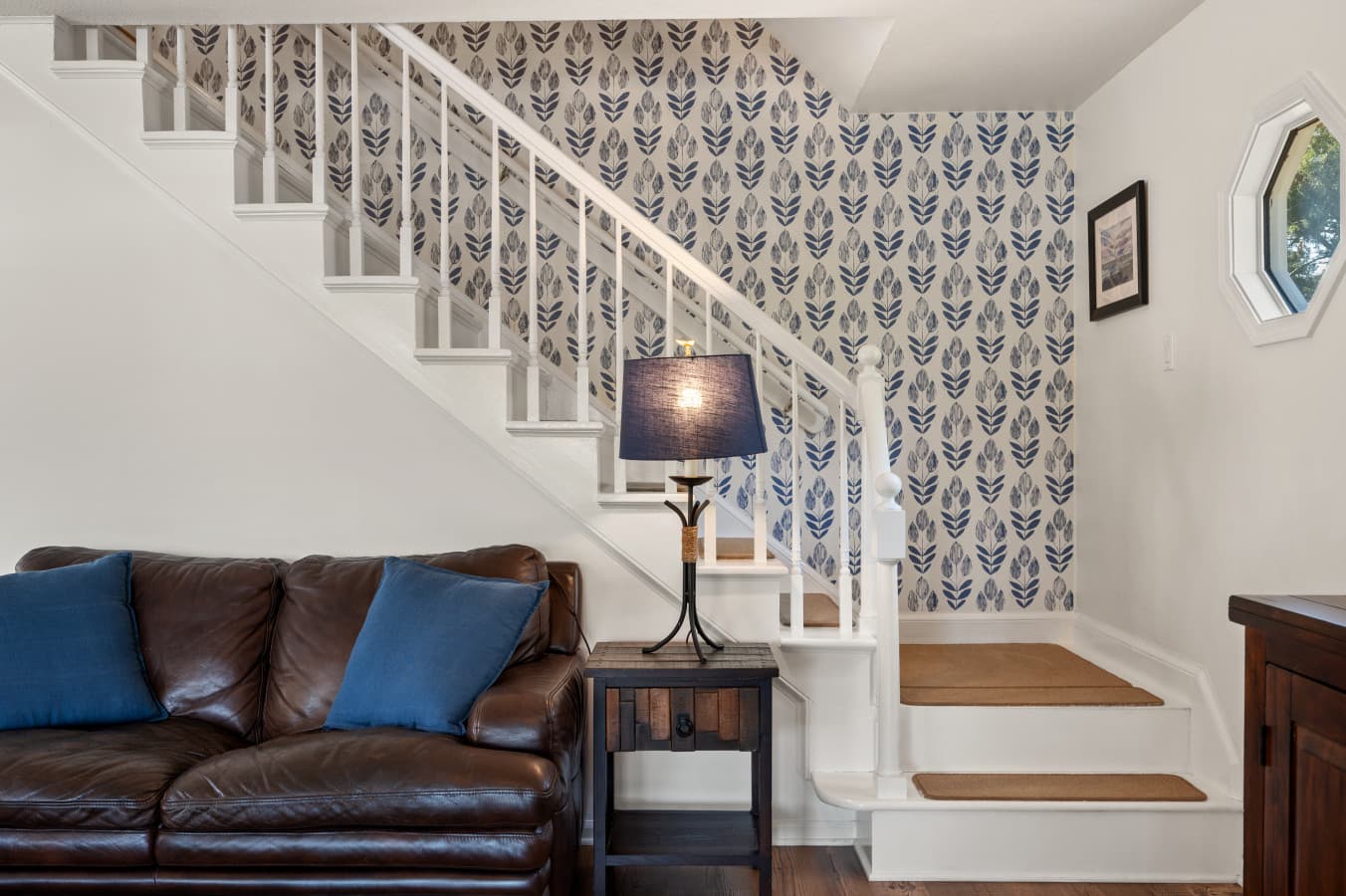 Cozy living room w/ sectional sofa and patterned staircase adding a fun design touch.