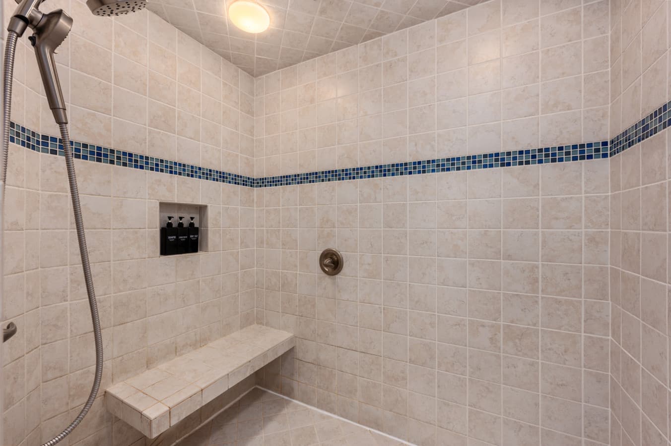 Walk-in shower w/ tile walls and simple fixtures for a clean, refreshing start.
