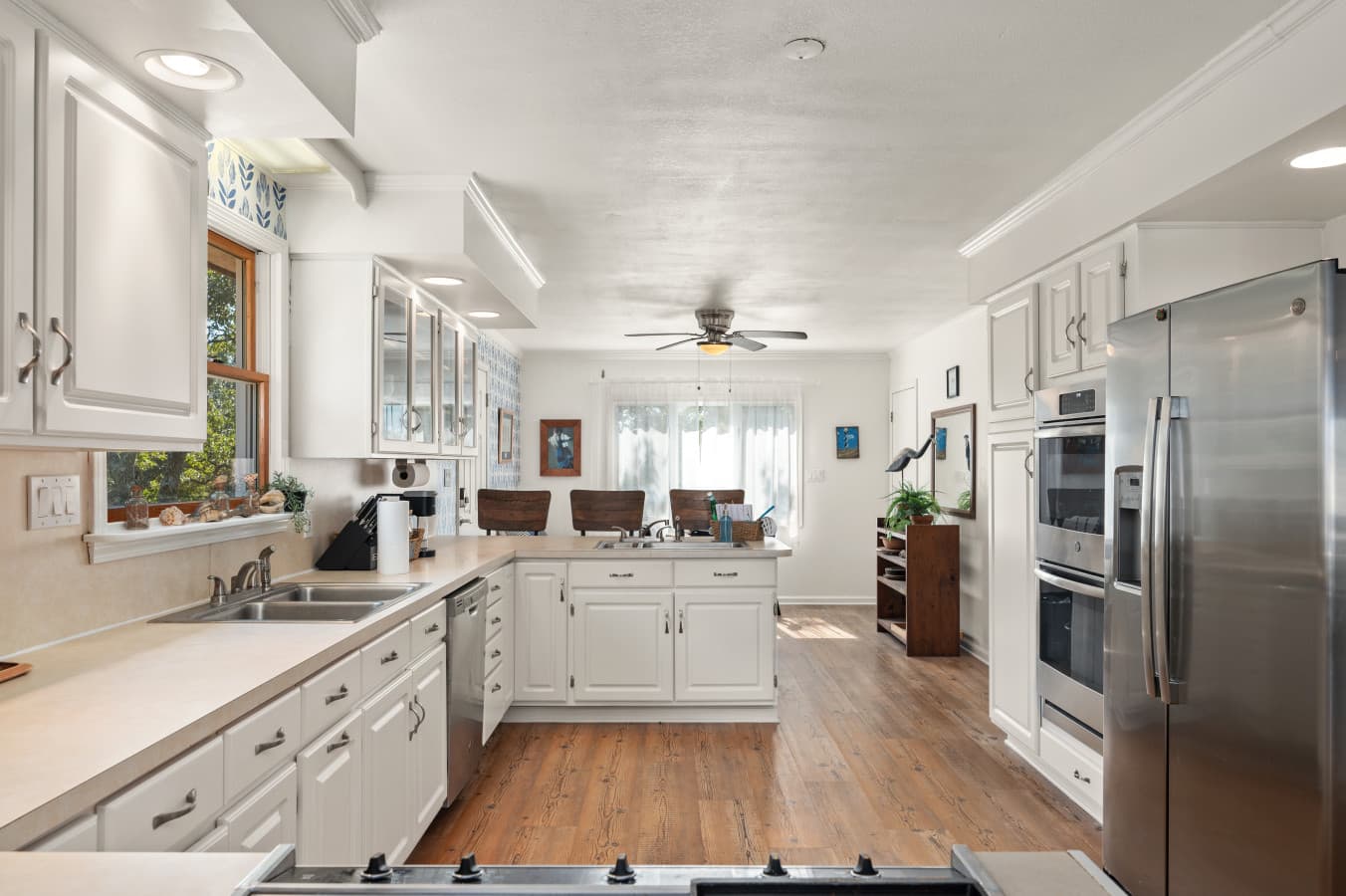 Long kitchen w/ white cabinets and plenty of counter space, designed for easy cooking.