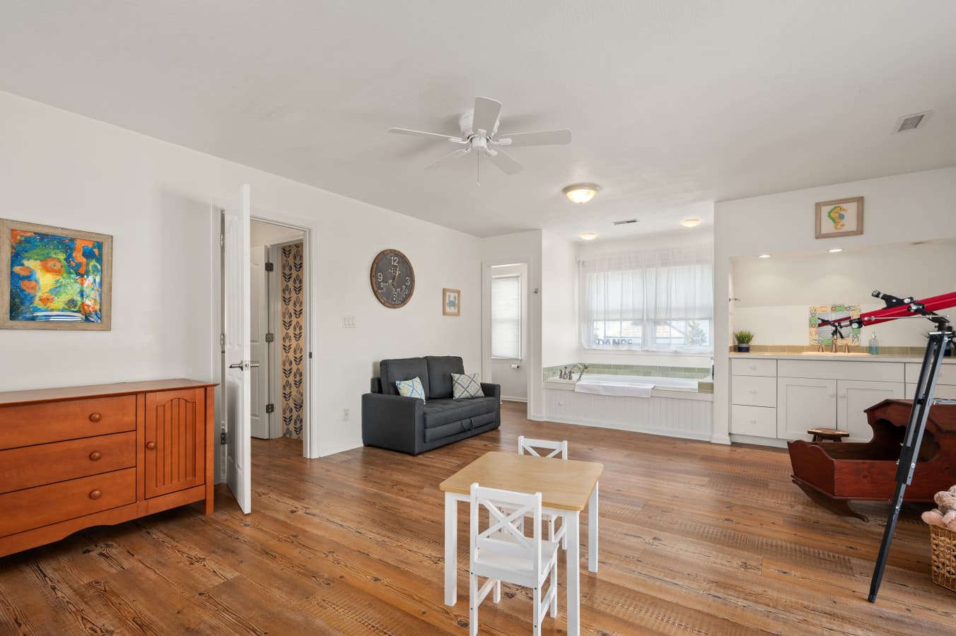 Comfortable living area w/ dresser, seating, & open view into the kitchen and dining space.