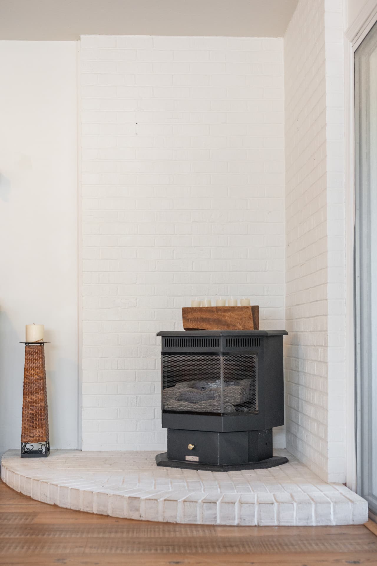 Corner wood stove on a white brick hearth, a cozy anchor for cool coastal evenings.
