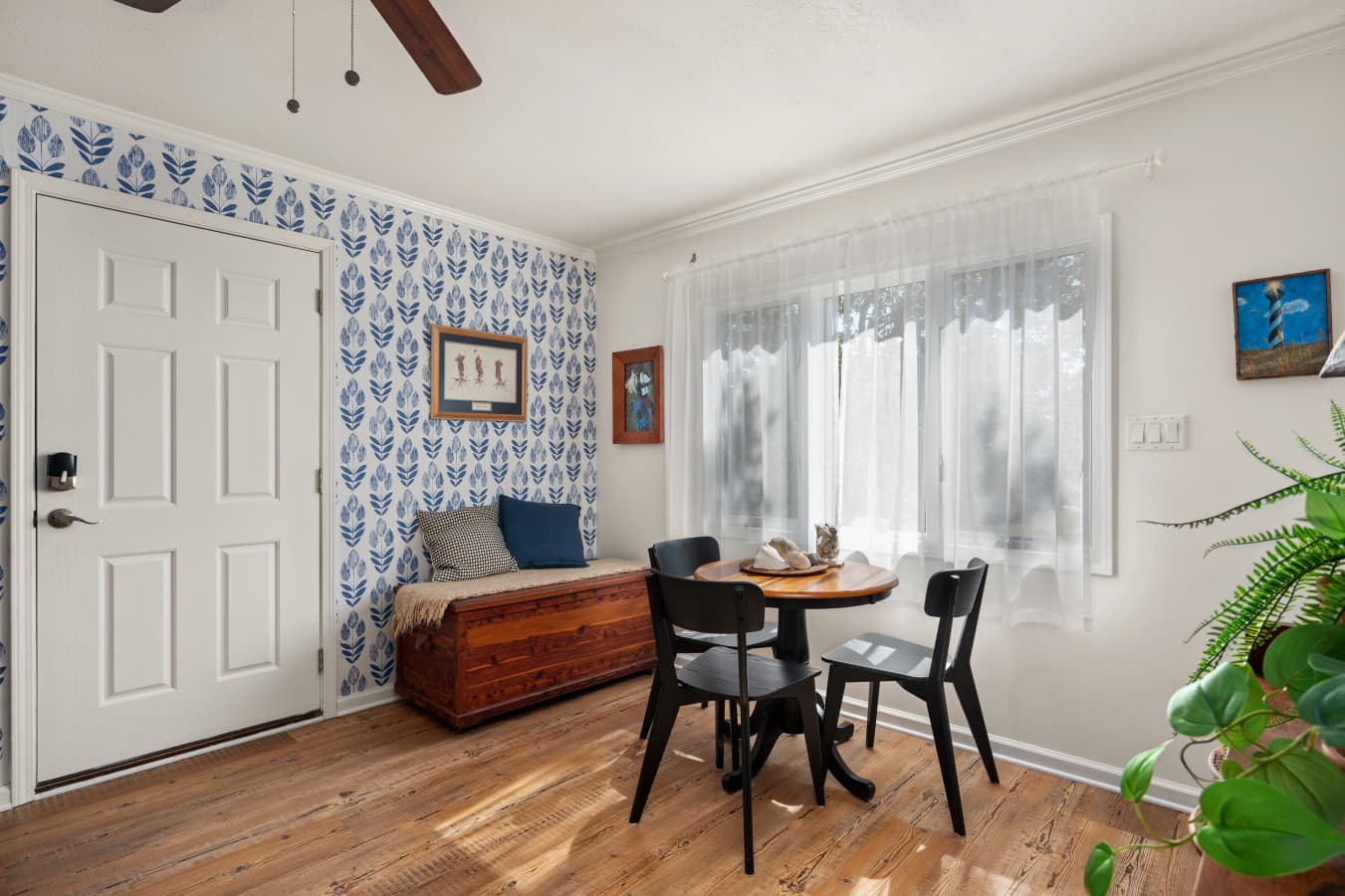 Entry & dining area w/ round table, bench seating & blue botanical wallpaper for coastal character.