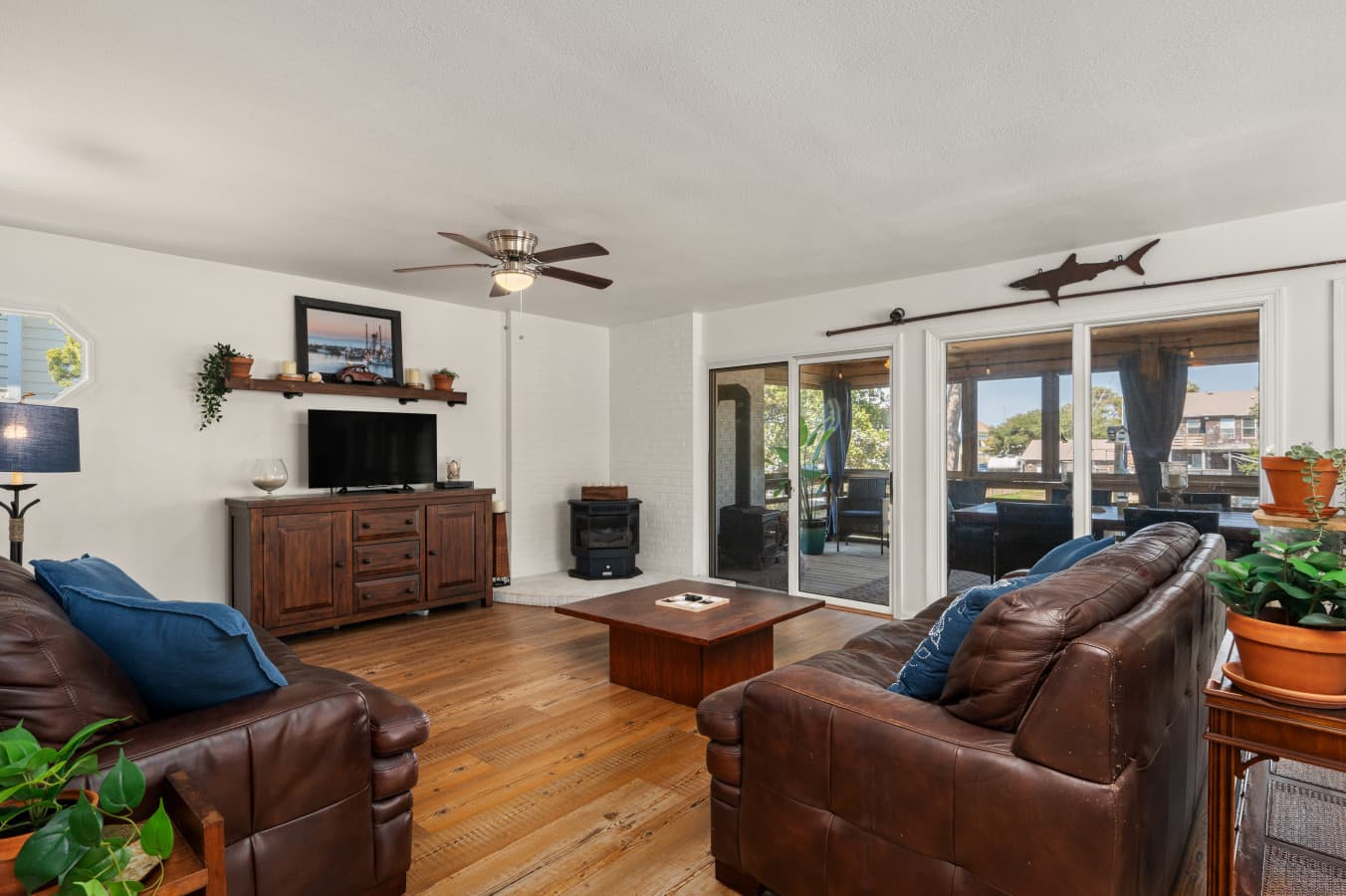 Living room w/ leather seating, TV console & glass doors opening to the screened porch.