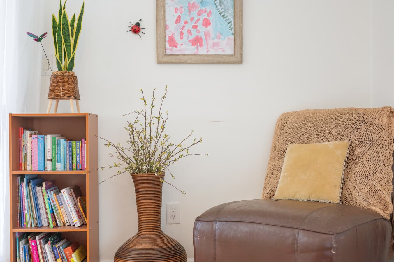 Reading corner w/ a bookcase of children's books, leather chair & artwork for quiet downtime.